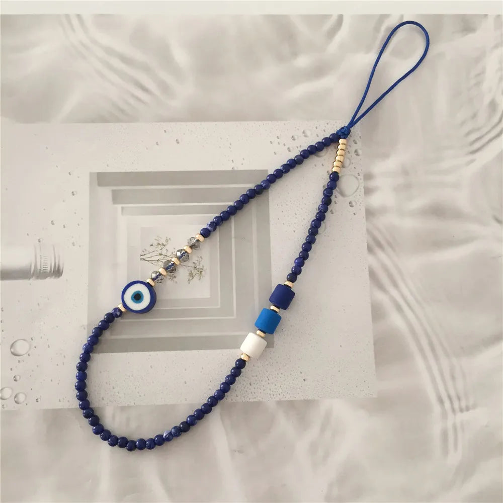 Blue beaded necklace with an evil eye charm on a textured surface