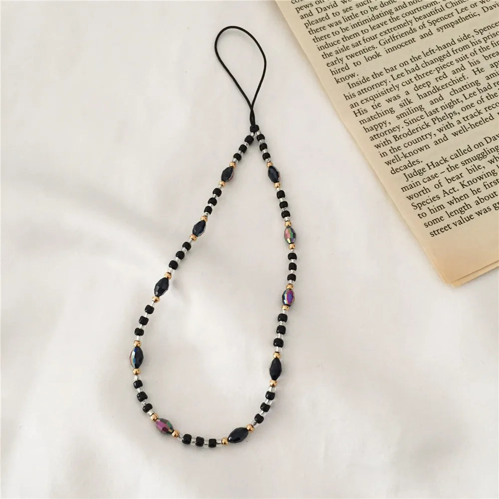 Beaded necklace with black and gold beads on a white surface with a book in the background