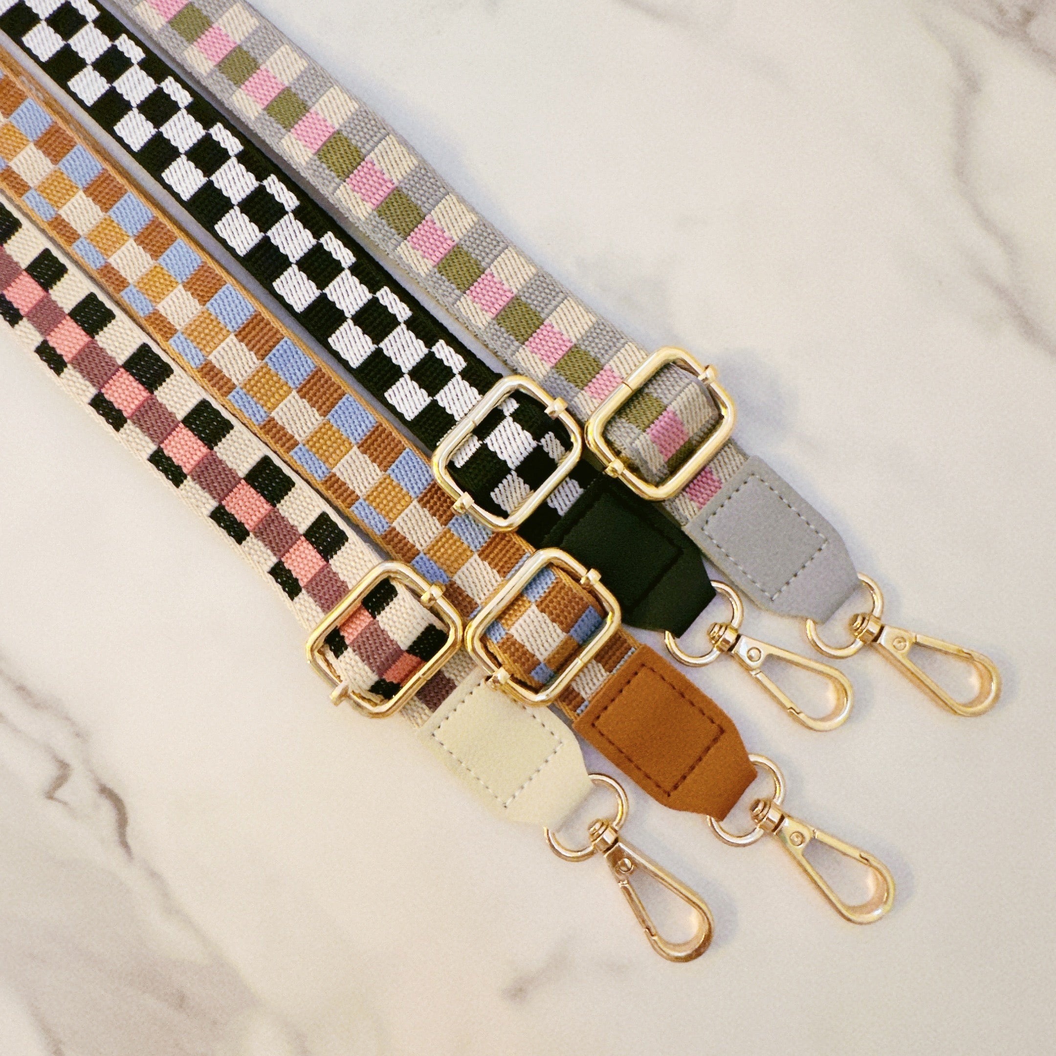 Set of colorful woven phone crossbody straps with gold buckles on a light background