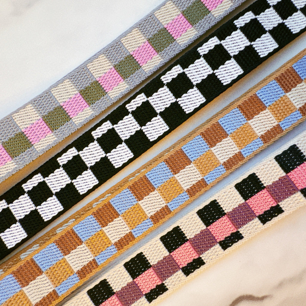 Four woven straps with different checkered patterns on a light background