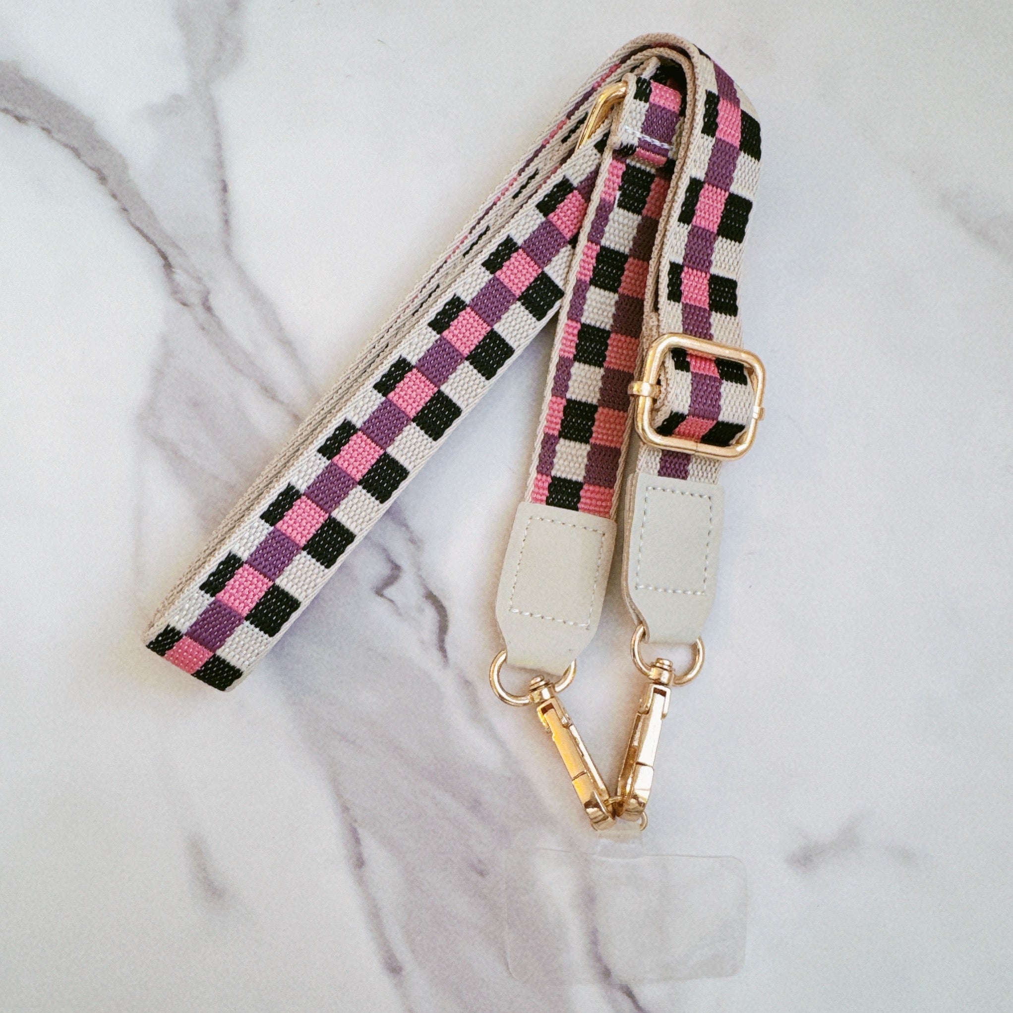 Checkered phone crossbody with gold hardware on a marble surface